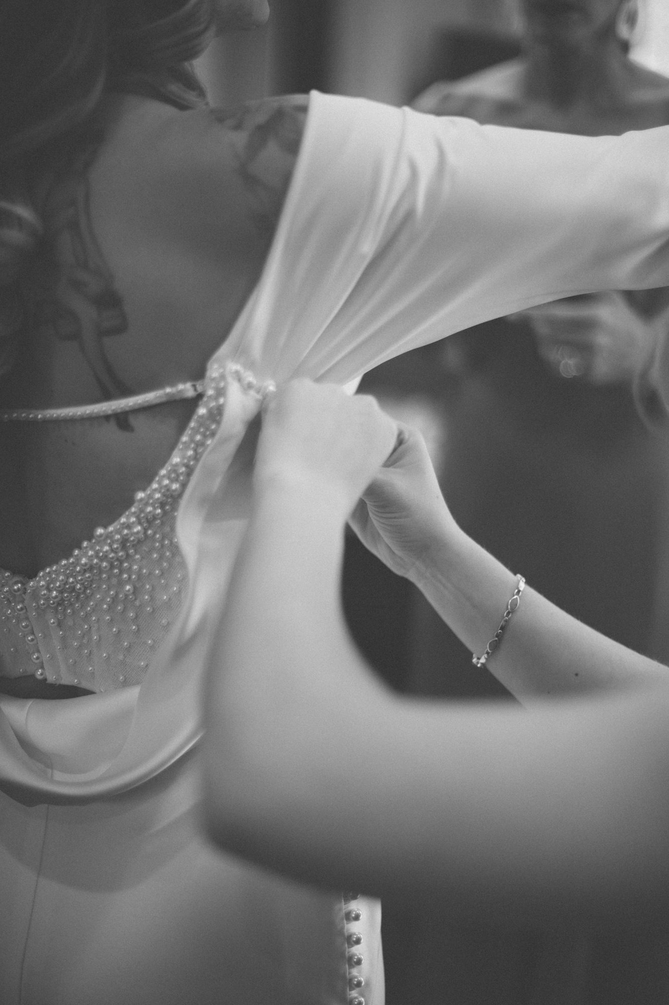 Bride getting ready, lacing the back of the dress, intimate detail captured by Manuel & Alma